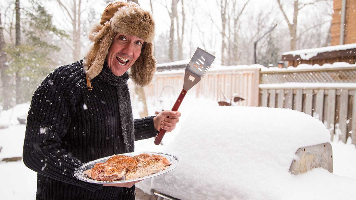 Mann grillt im Schnee